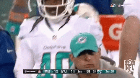 A Man Wearing A Dolphins Jersey Is Watching A Game GIF