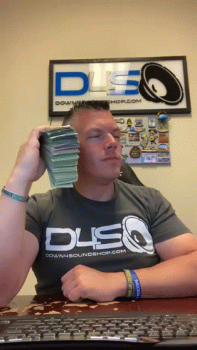 A Man Wearing A Downsoundshop.com Shirt Is Holding A Stack Of Money In Front Of His Face GIF