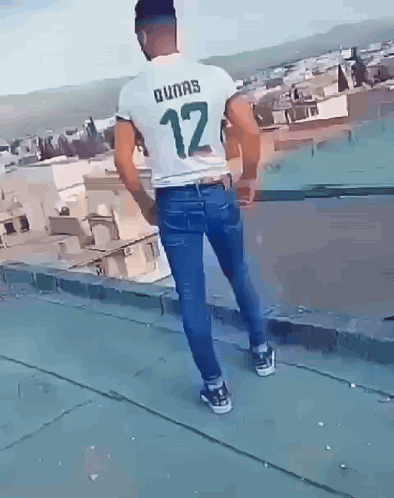 A Man Wearing A Dunas 12 Shirt Is Standing On A Rooftop GIF
