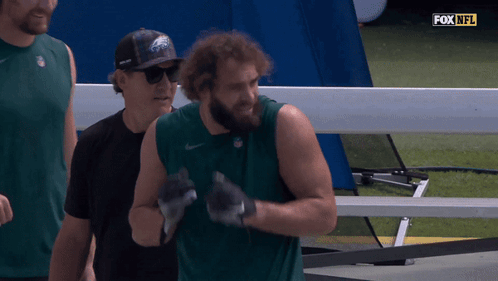 a man wearing a eagles hat stands next to a man wearing a black shirt