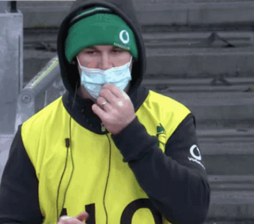A Man Wearing A Face Mask And A Green Hat With The Number 0 On It GIF