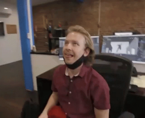 A Man Wearing A Face Mask Is Sitting In A Chair In An Office . GIF