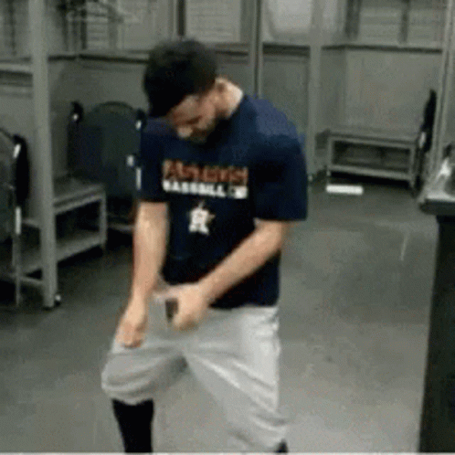 A Man Wearing A Famous Baseball Shirt Is Dancing In A Locker Room . GIF