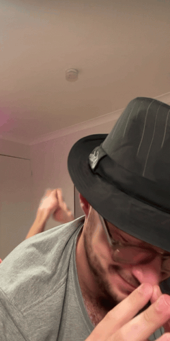 A Man Wearing A Fedora Hat With A Skull On It GIF