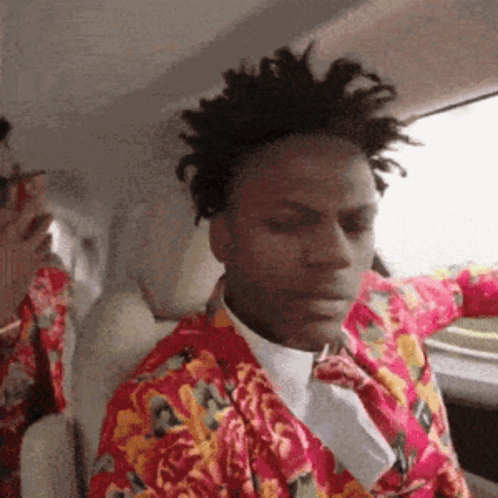 A Man Wearing A Floral Shirt And Tie Is Sitting In A Car GIF