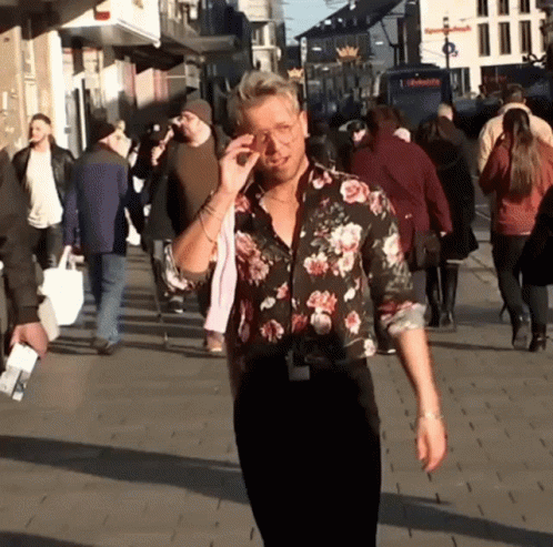 A Man Wearing A Floral Shirt Is Walking Down A Street GIF