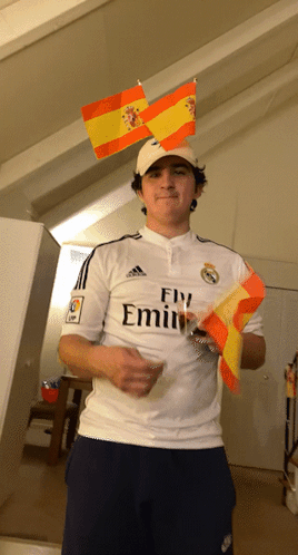 A Man Wearing A Fly Emirates Shirt Is Holding A Small Spanish Flag GIF