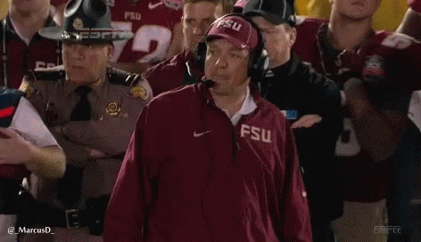 a man wearing a fsu jacket is standing in front of a crowd .