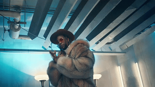A Man Wearing A Fur Coat And A Hat Holds A Gun GIF