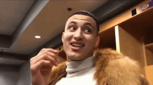A Man Wearing A Fur Coat And A White Turtleneck Is Standing In A Locker Room GIF