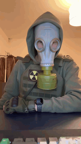A Man Wearing A Gas Mask And A Hoodie Has A Watch On His Wrist That Shows The Time As 8:30 GIF