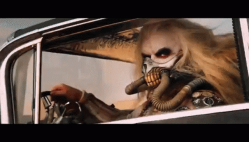 A Man Wearing A Gas Mask Is Driving A Car In The Desert . GIF