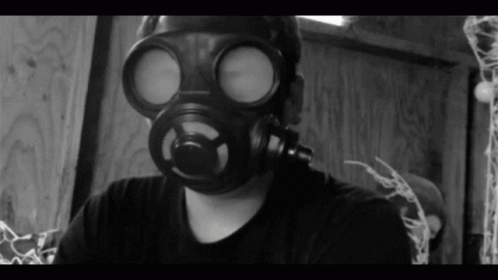 A Man Wearing A Gas Mask Is Looking At The Camera GIF