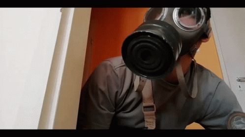 A Man Wearing A Gas Mask Is Looking Out A Door GIF