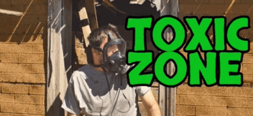 A Man Wearing A Gas Mask Stands In Front Of A Sign That Reads Toxic Zone GIF