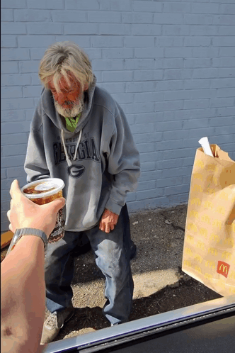 A Man Wearing A Georgia Sweatshirt Is Kneeling Down Next To A Mcdonald 'S Bag GIF