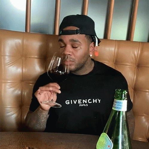 A Man Wearing A Givenchy Shirt Is Drinking Wine GIF