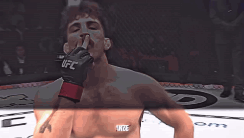 A Man Wearing A Glove That Says Ufc Holds His Finger To His Mouth GIF