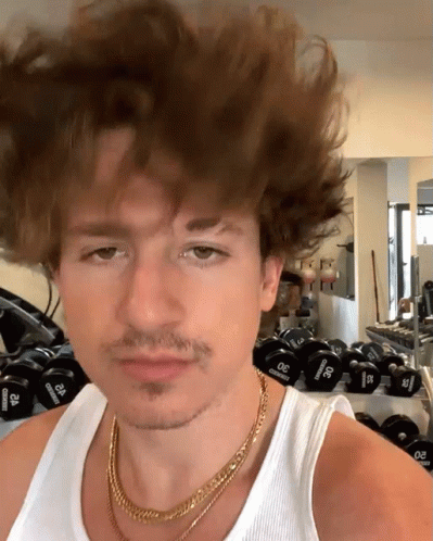 A Man Wearing A Gold Chain And A White Tank Top Stands In Front Of A Row Of Dumbbells That Say 30 Pounds GIF