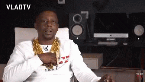 A Man Wearing A Gold Chain Around His Neck Is Sitting In Front Of A Vlad Tv Logo GIF