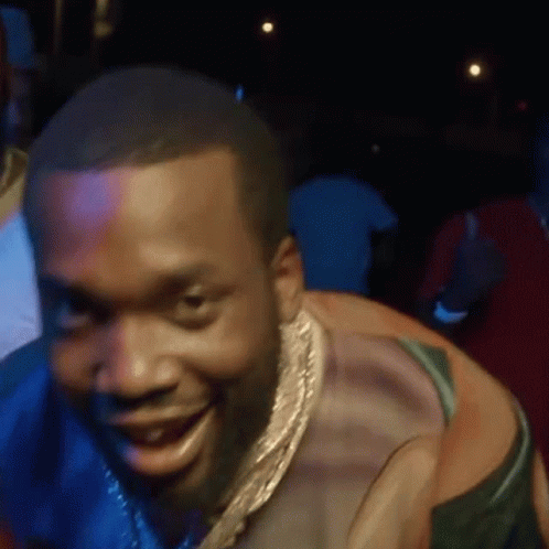 A Man Wearing A Gold Chain Around His Neck Is Smiling . GIF