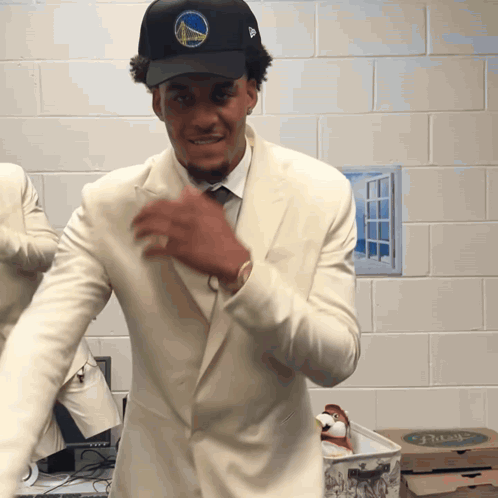 A Man Wearing A Golden State Warriors Hat And White Suit GIF