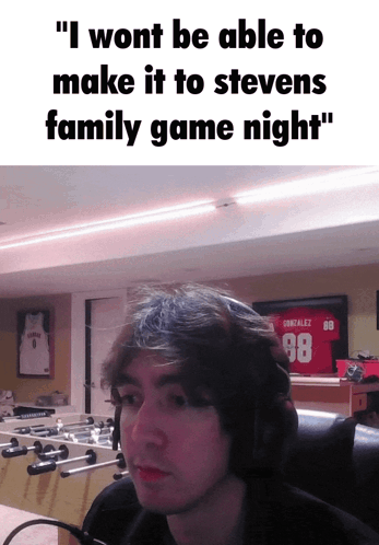 A Man Wearing A Gonzalez 98 Jersey Sits In Front Of A Foosball Table In A Room GIF