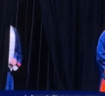 a man wearing a graduation cap and gown is dancing on a stage .