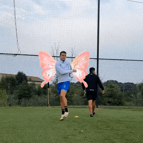 A Man Wearing A Gray Jacket And Blue Shorts Has Pink Wings On His Arms GIF