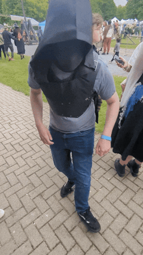 A Man Wearing A Gray Shirt And Blue Wristband Walking On A Brick Sidewalk GIF