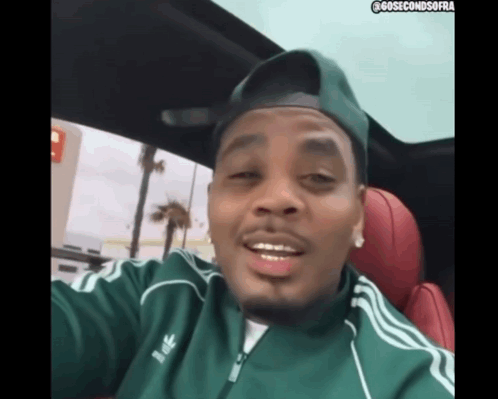A Man Wearing A Green Adidas Jacket And A Hat GIF