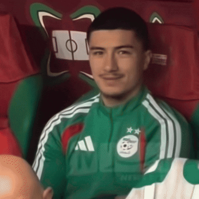 a man wearing a green adidas jacket is sitting in a chair