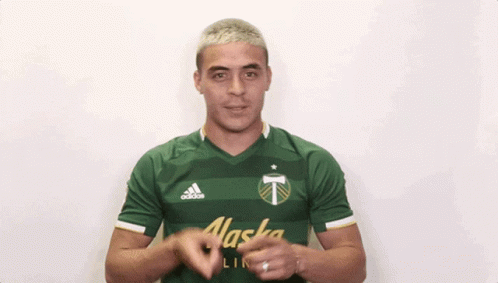 A Man Wearing A Green Alaska Shirt Is Clapping His Hands GIF