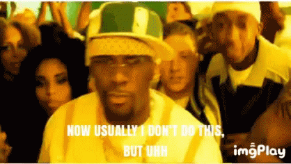 A Man Wearing A Green And White Hat Is Standing In Front Of A Crowd . GIF