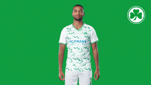 a man wearing a green and white hofmann jersey stands in front of a green background