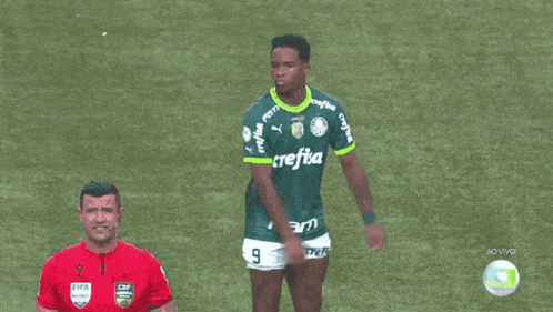 a man wearing a green crefisa jersey stands on a soccer field