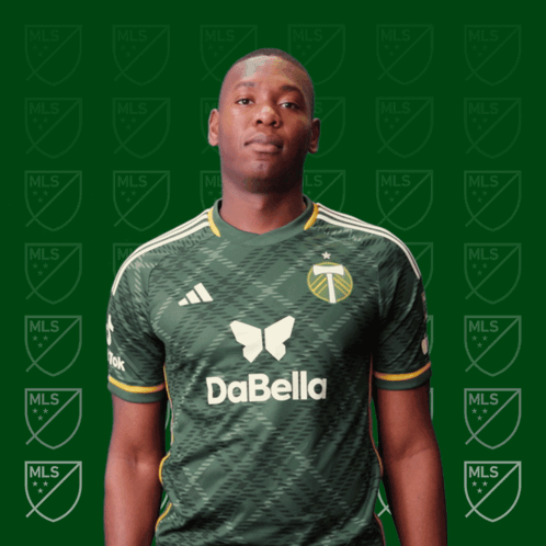 A Man Wearing A Green Dabella Jersey Stands In Front Of A Green Background GIF