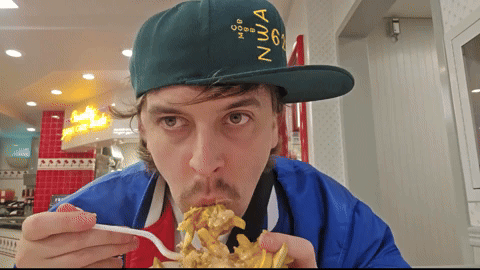 A Man Wearing A Green Hat With The Number 6 On It Is Eating French Fries GIF