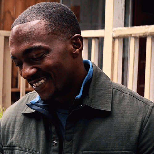 A Man Wearing A Green Jacket And A Blue Shirt Smiles With His Eyes Closed GIF