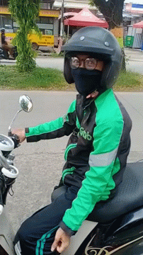 A Man Wearing A Green Jacket That Says Grab Is Sitting On A Motorcycle GIF