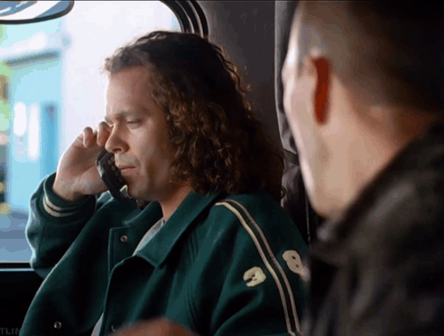 A Man Wearing A Green Jacket With The Number 8 On It Talks On A Cell Phone GIF