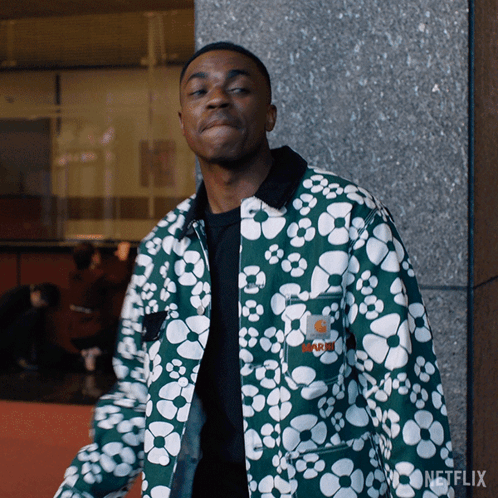 A Man Wearing A Green Jacket With White Flowers Has A Netflix Logo On The Bottom Right GIF