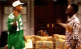 A Man Wearing A Green Jersey With The Number 12 On It Talks To Another Man GIF