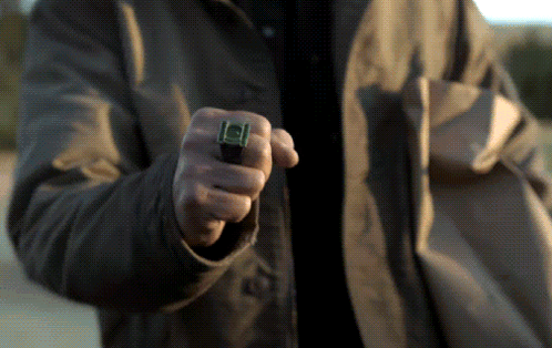 a man wearing a green lantern ring is pointing at something