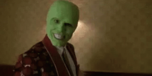 A Man Wearing A Green Mask Is Sitting On A Bed In A Room . GIF