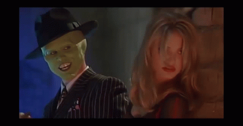 A Man Wearing A Green Mask Is Standing Next To A Woman In A Red Dress GIF
