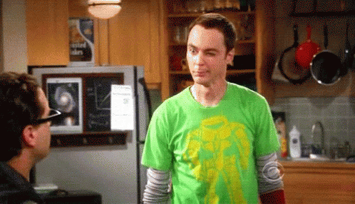 A Man Wearing A Green Shirt Is Standing In A Kitchen Next To A Refrigerator . GIF
