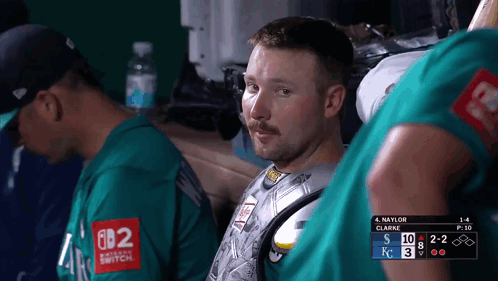 A Man Wearing A Green Shirt That Says Nintendo Switch Sits In A Dugout GIF