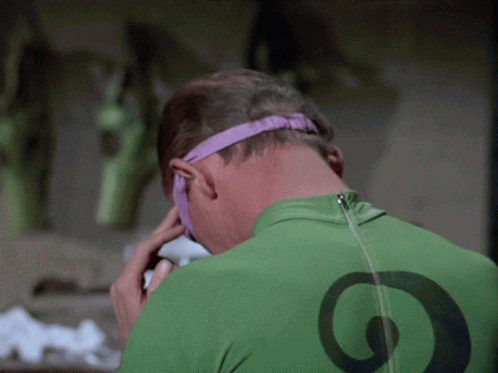 A Man Wearing A Green Shirt With A Black Circle On The Back Is Talking On A Cell Phone GIF