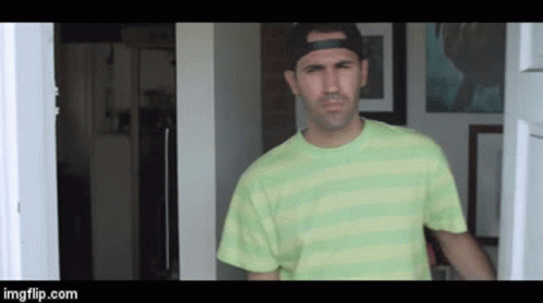 a man wearing a green striped shirt and a black hat is standing in a doorway ..